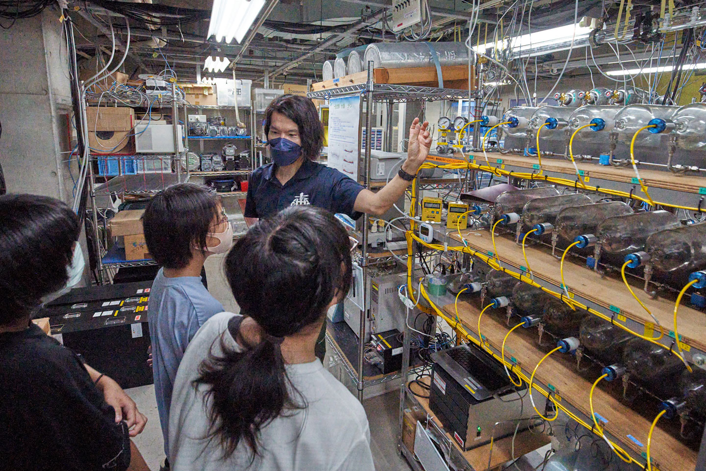 写真6 先ほど学校での授業で聞いた観測機器を間近に見ながら、しっかりと説明を聞く子どもたち。