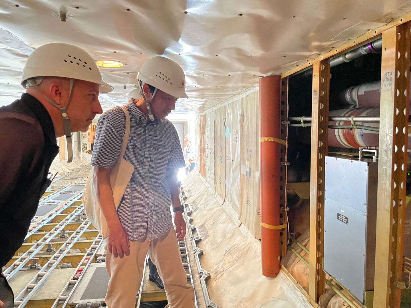 写真３　日本航空の格納庫にてCONTRAILの観測機を見学。地球システム領域町田敏暢室長が航空機に搭載する連続二酸化炭素測定装置（CME）の説明（写真提供: 企画部国際室小林新係員）。