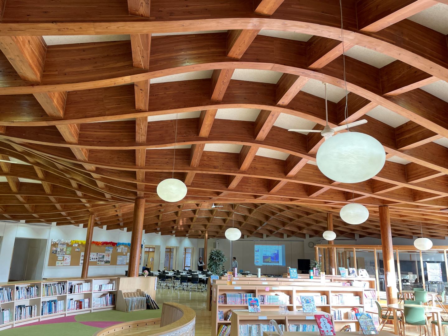 写真1 足を踏み入れてびっくり。波打つような木造の天井が特徴的な陸別小学校です。手前が図書スペース、奥が今回授業を行う多目的ホール。