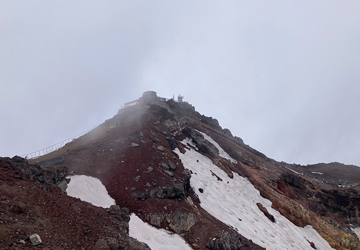 写真1. 残雪が見られる7月初旬の富士山頂。建物は富士山特別地域気象観測所(旧富士山測候所)。
