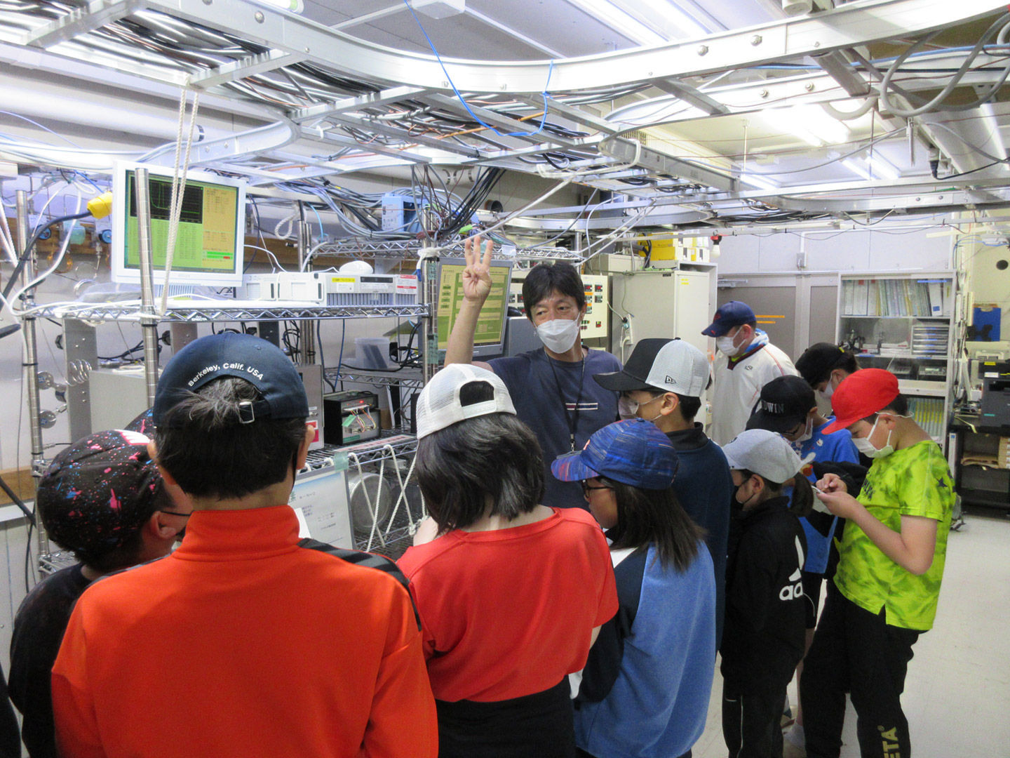 写真2 ステーション内に設置されている観測機器について説明を受ける子どもたち